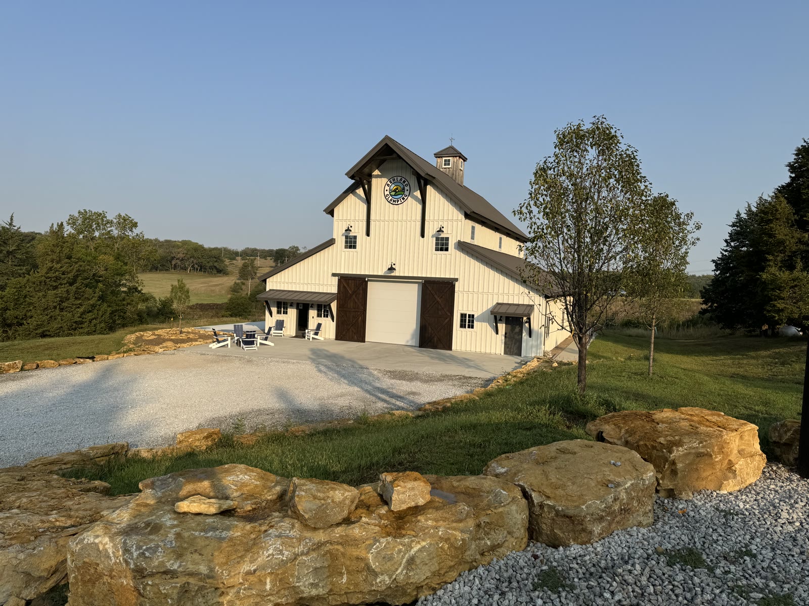 The white Ashland Glamping barn at golden hour, patio chairs out front